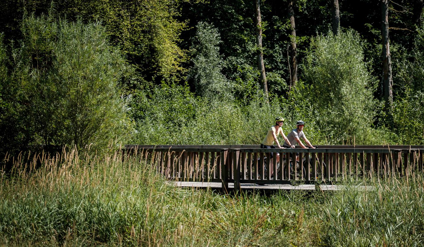 Zwei Radfahrer auf einer Brücke entlang eines Radwegs