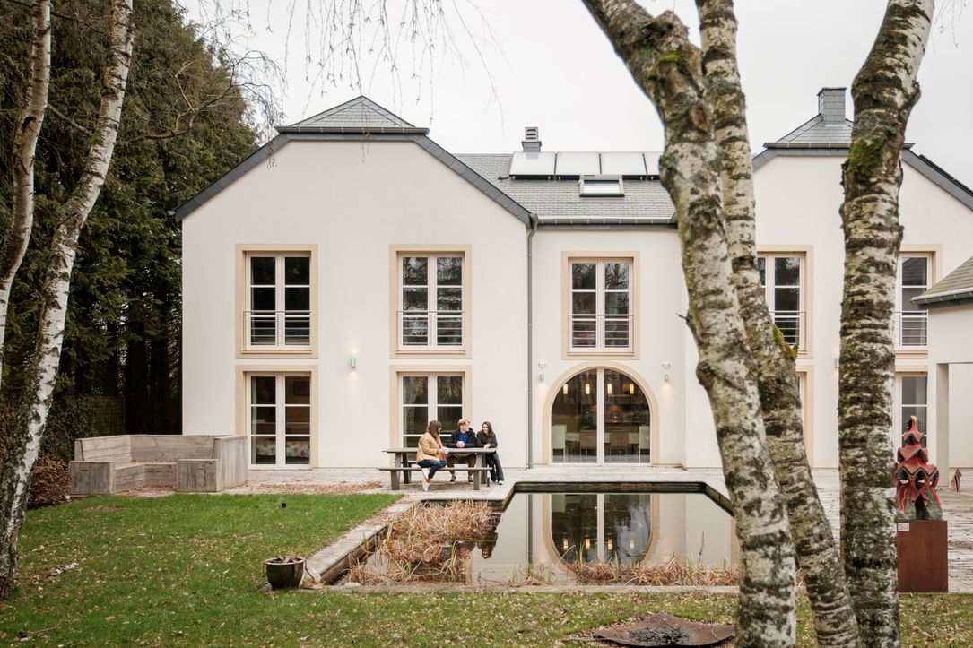 Drei Personen sitzen zusammen auf der Bank vor dem B&B White Pearl