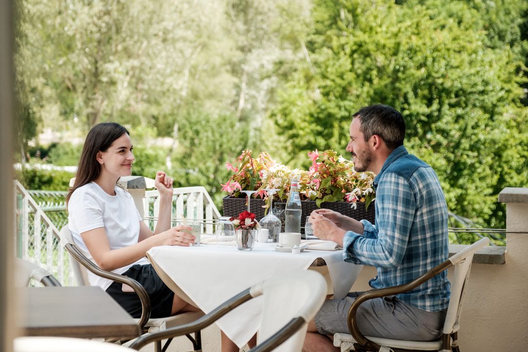 Two people sitting together at a table on the terrace of a restaurant