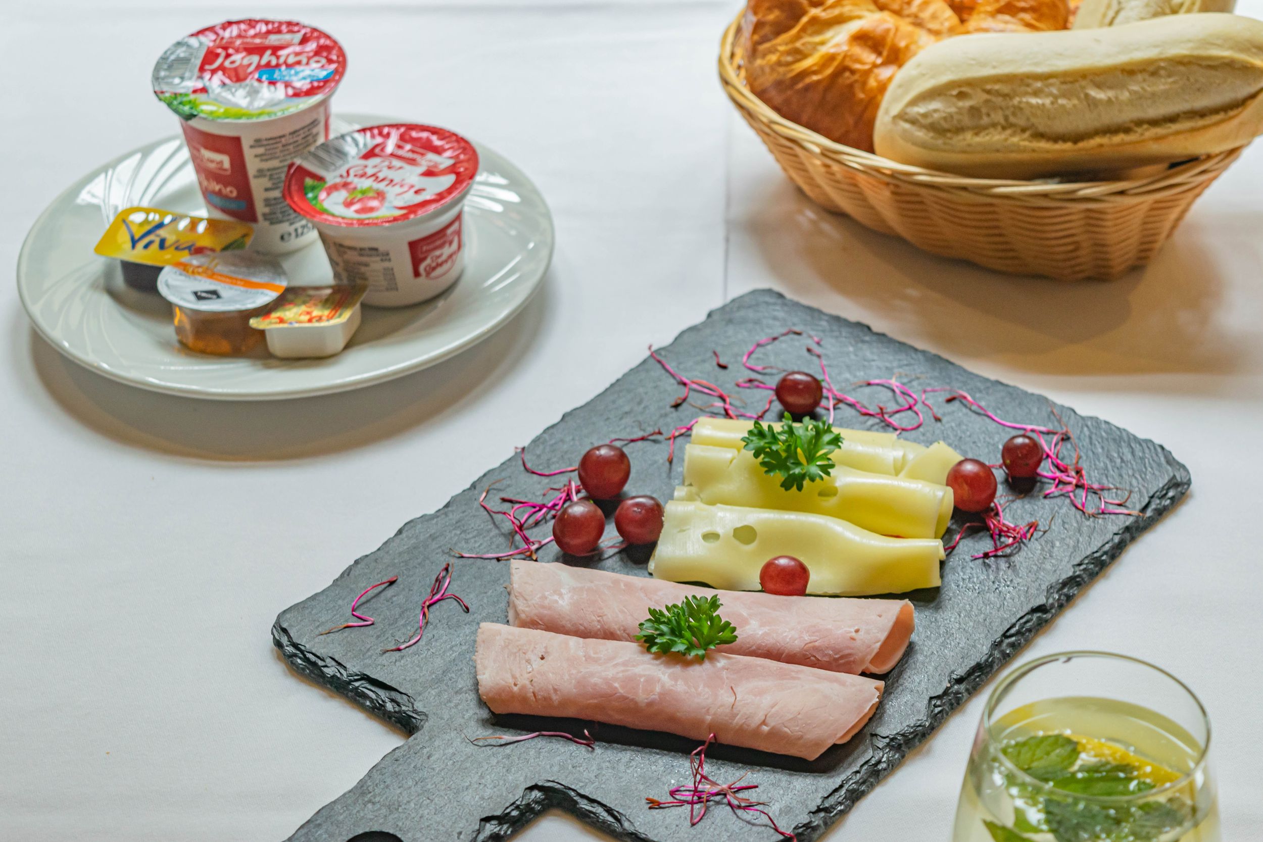 Joghurt, Brötchen, Käse und Schinken auf dem Frühstückstisch