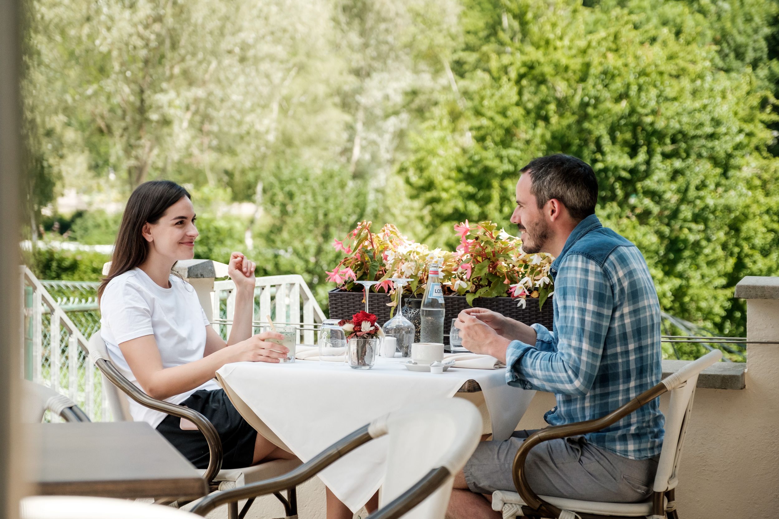 Two people sitting together at a table on the terrace of a restaurant