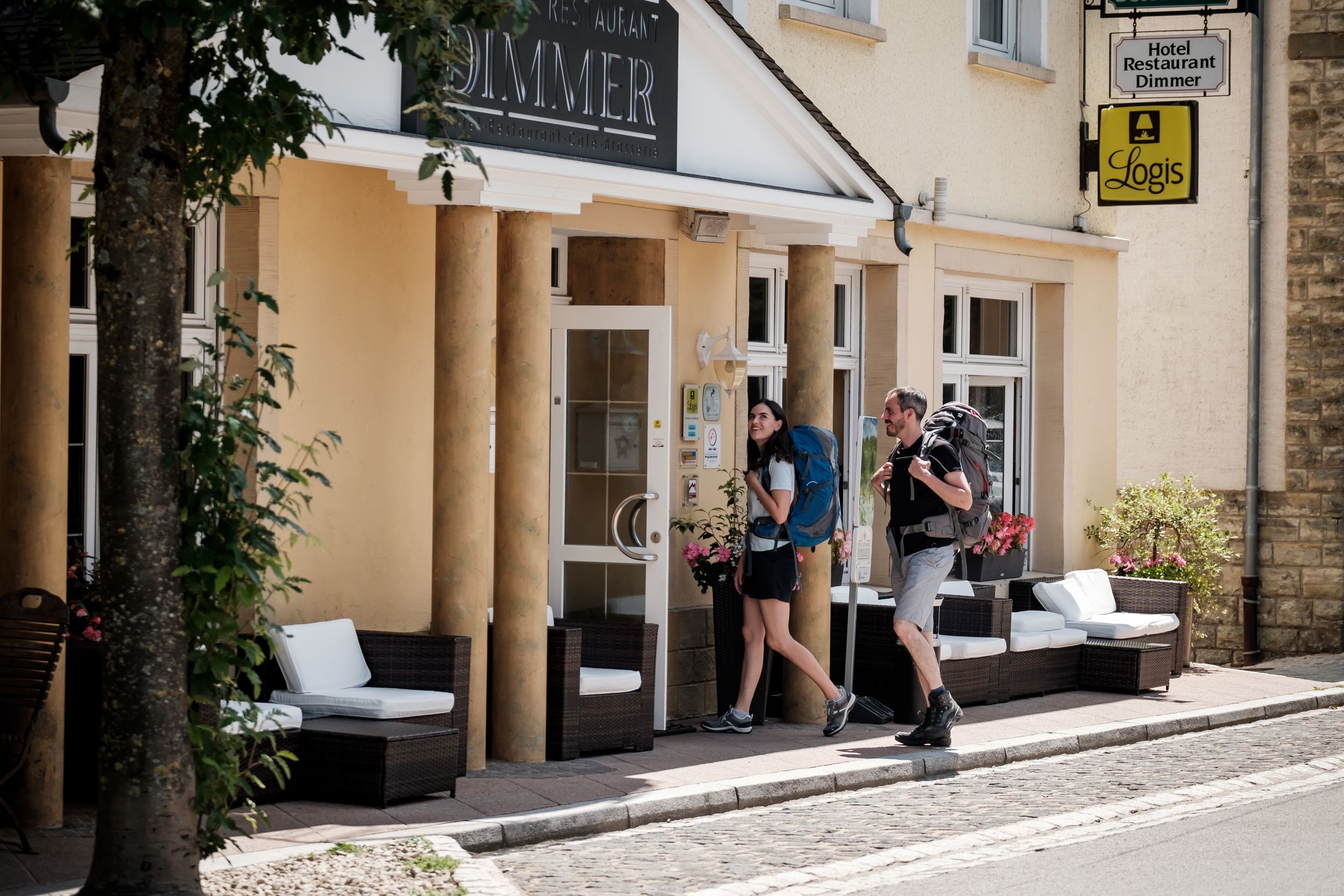 Two people entering Hotel Dimmer with hiking backpacks