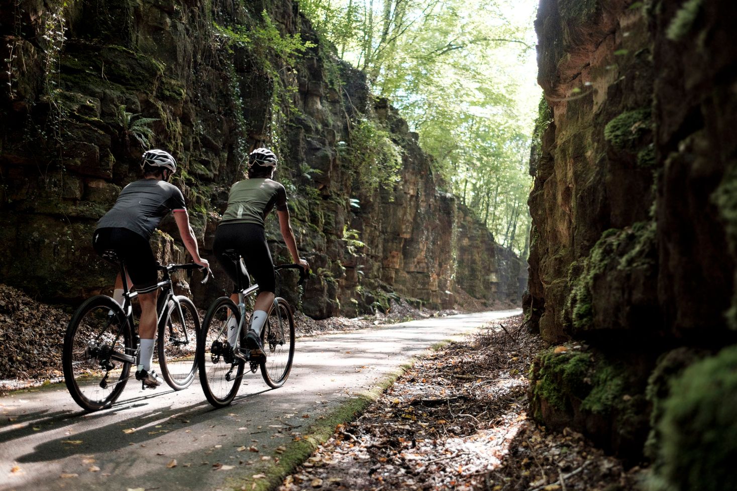 Two cyclists on a forest path with rocks