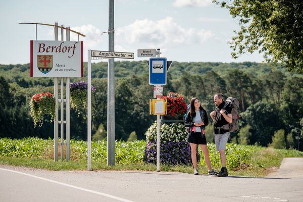 Twee personen wachten op de bus bij de bushalte in Berdorf