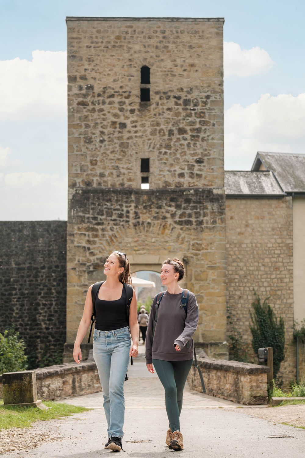 Two visitors walking near Larochette Castle's stone entrance